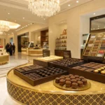 Elegant luxury chocolate display in a Dubai boutique with chandeliers and gold accents.