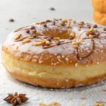 A freshly baked Protein Donut Recipe, topped with a drizzle of chocolate, chopped nuts, and a dusting of powdered sugar.