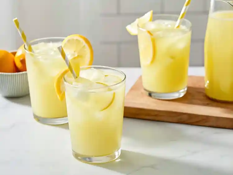 Whole lemon lemonade ingredients displayed in glass bowls including lemons, sugar, and water.