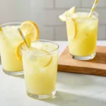 Whole lemon lemonade ingredients displayed in glass bowls including lemons, sugar, and water.