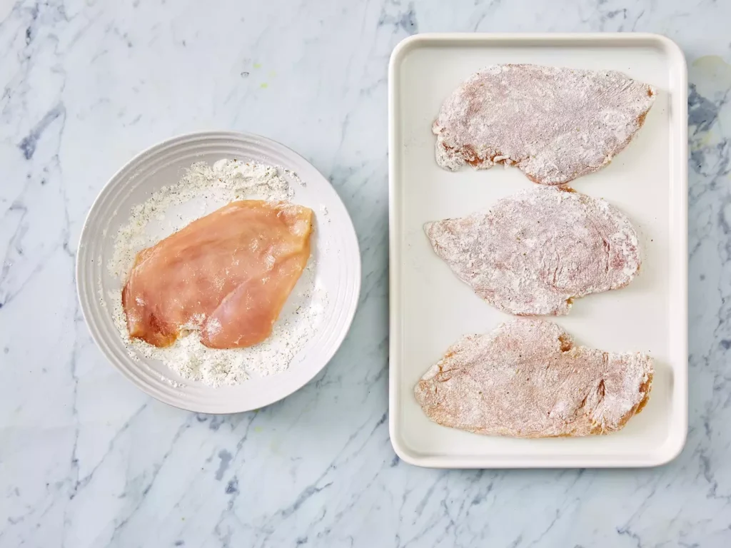Raw chicken breast coated in seasoned flour for Chicken Marsala preparation